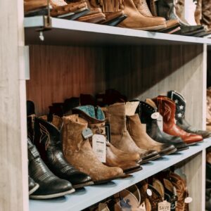 A variety of cowboy boots on display in a retail store, highlighting styles and material.
