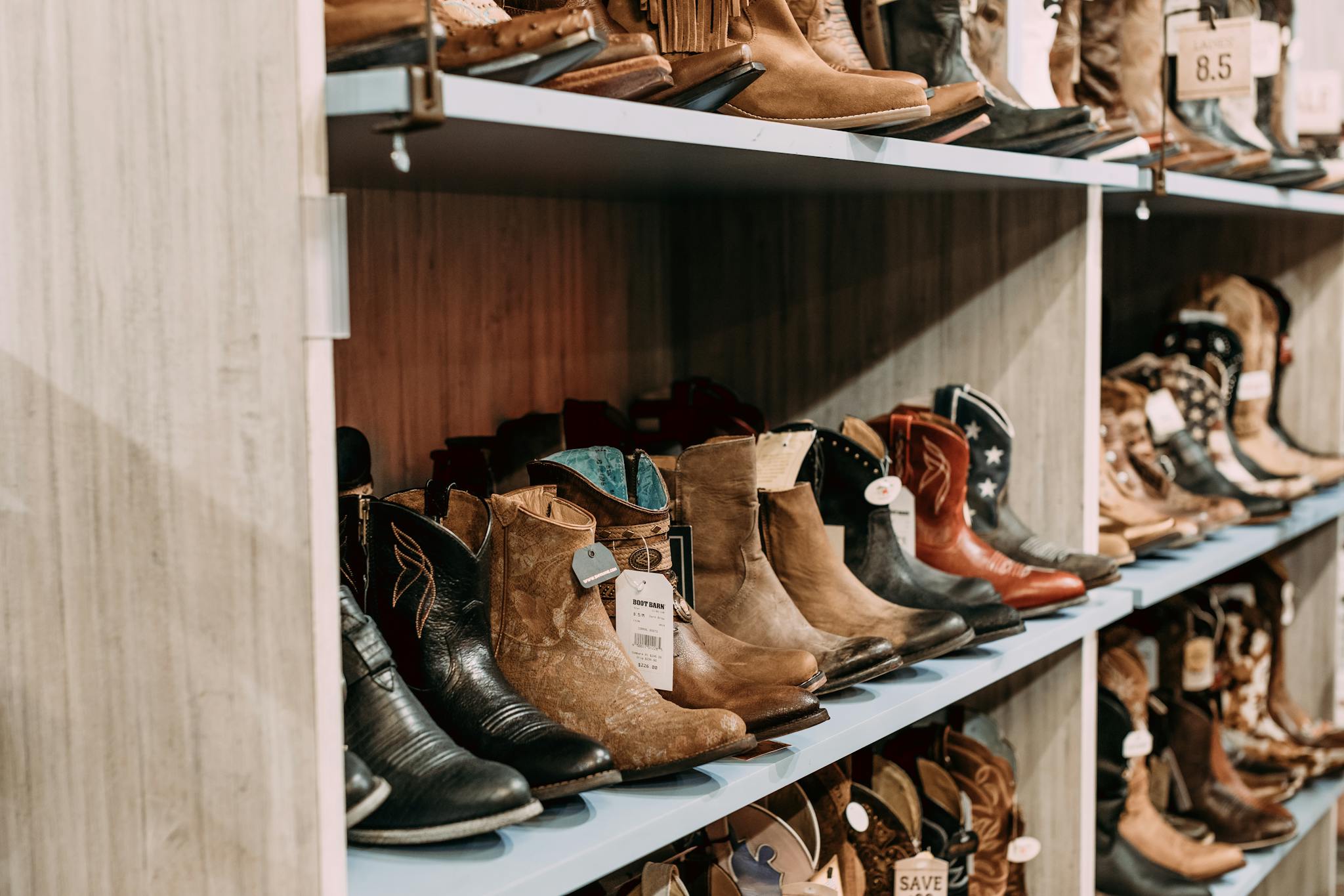 A variety of cowboy boots on display in a retail store, highlighting styles and material.